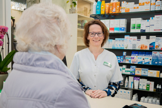 Apothekersassistente Henne van der Slik met klant aan de balie