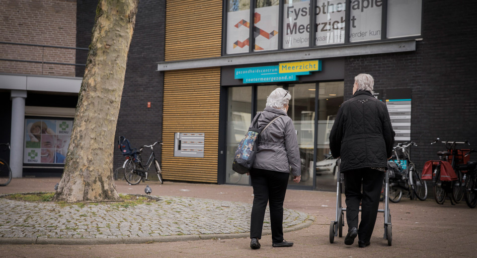 Ouder echtpaar loopt naar ingang gezondheidscentrum